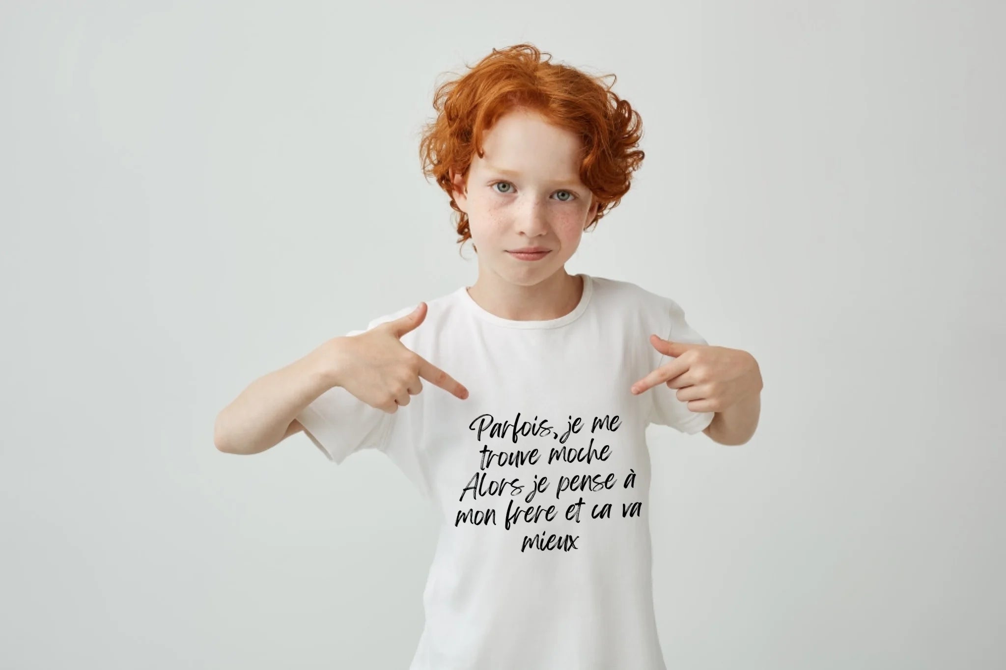 gros-plan-d-un-garcon-mignon-aux-cheveux-rouges-avec-des-taches-de-rousseur-pointant-avec-les-doigts-sur-un-t-shirt-blanc-avec-une-expression-serieuse-et-confiante-copiez-l-espace